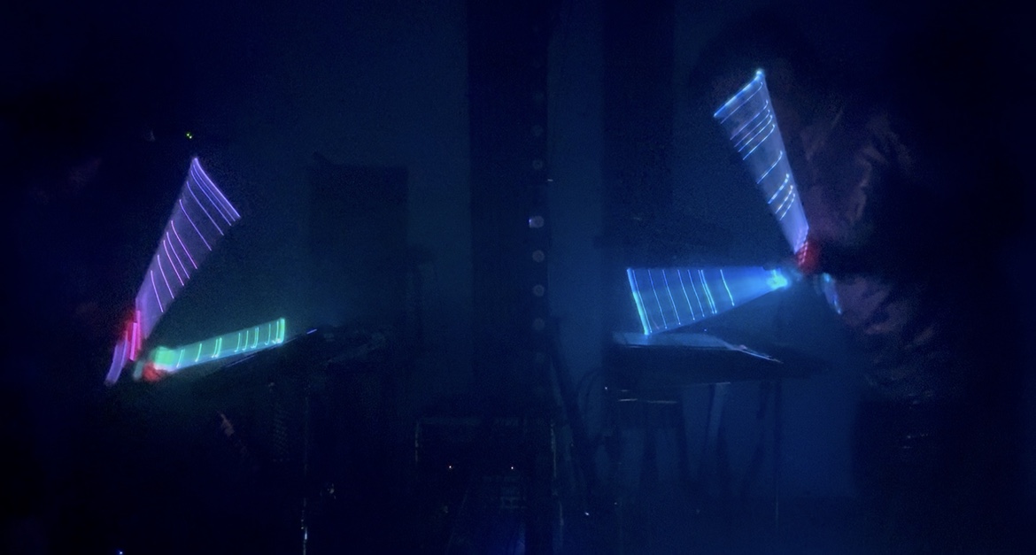 Illuminated keyboard stands glowing in blue and pink light