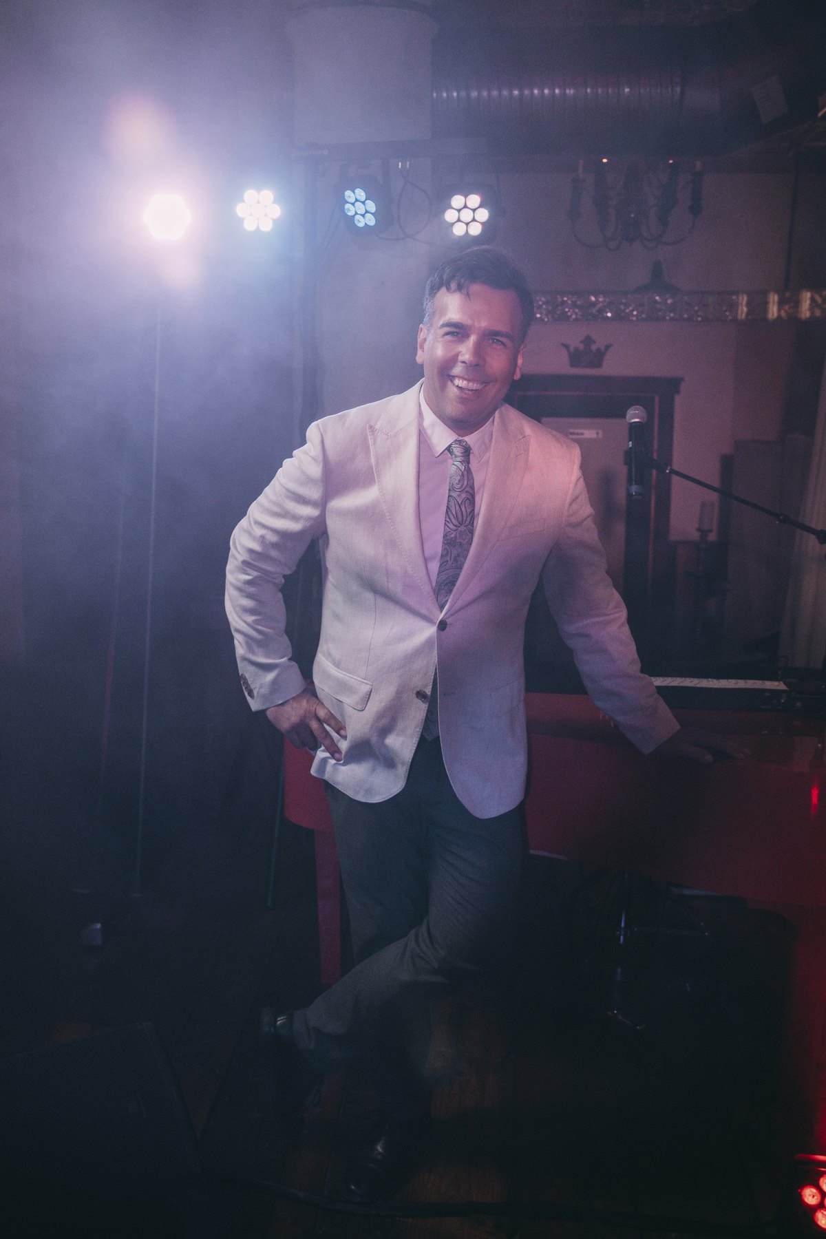 Paul Seiz, DJ PJS, smiling beside a red piano